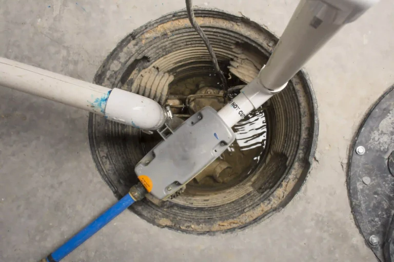 A Halls Rooter & Plumbing sump pump installed in a circular pit, connected to sturdy PVC pipes and set within a concrete floor. Some standing water is visible in the pit, illustrating this essential system at work to protect customers’ homes from water damage—especially important for residents in Midland and Odessa, TX, where extreme weather can lead to frozen or burst pipes.
